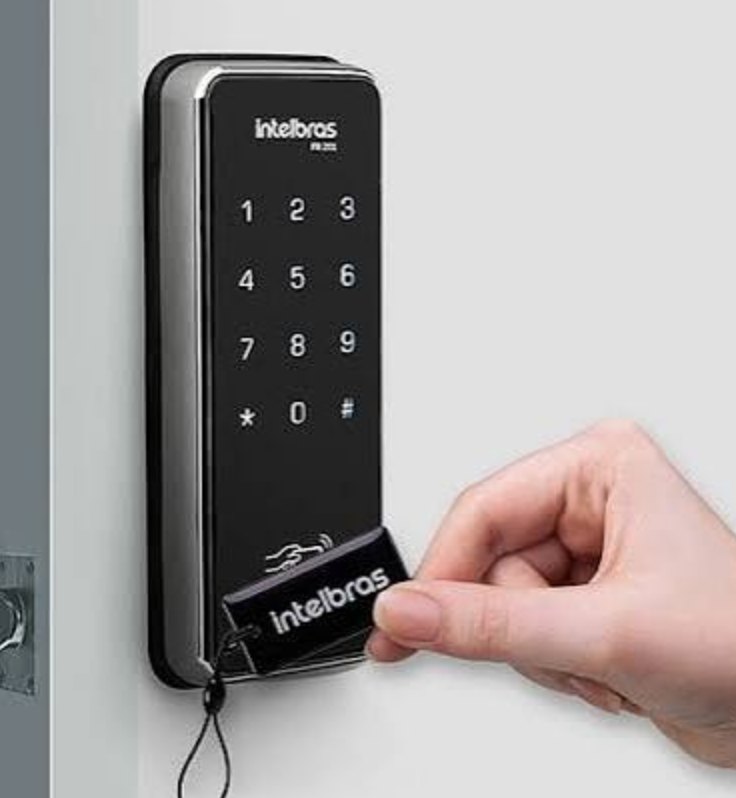 Fechadura digital instalada numa porta, com a mão aproximando a tag de acesso